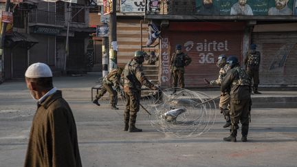 Un homme observe un groupe militaire indien dresser un barrage routier à Srinagar,&nbsp;l'un des bastions de la contestation du Cachemire indien, le&nbsp;13 janvier 2018.&nbsp; (ANTONI LALLICAN / HANS LUCAS / AFP)