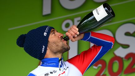 Le coureur français Thibaut Pinot célèbre, au champagne, sa victoire d'étape&nbsp;sur le Tour des Alpes, le 22 avril 2022 à Linz, en Autriche. (TIM DE WAELE / GETTY IMAGES)