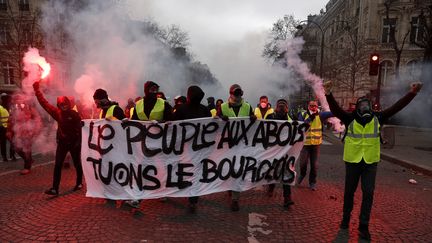 Des manifestants, portant des gilets jaunes, tiennent des fumigènes dans les mains. (MAXPPP)