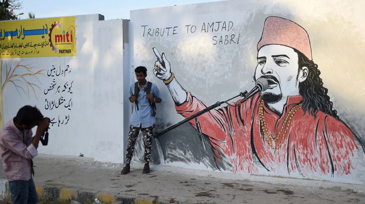 Un homme se fait photographier devant une fresque en hommage à Amjad Sabri, quelques jours après l'assassinat du chanteur pakistanais, en juin 2016
 (Asif Hassan / AFP)