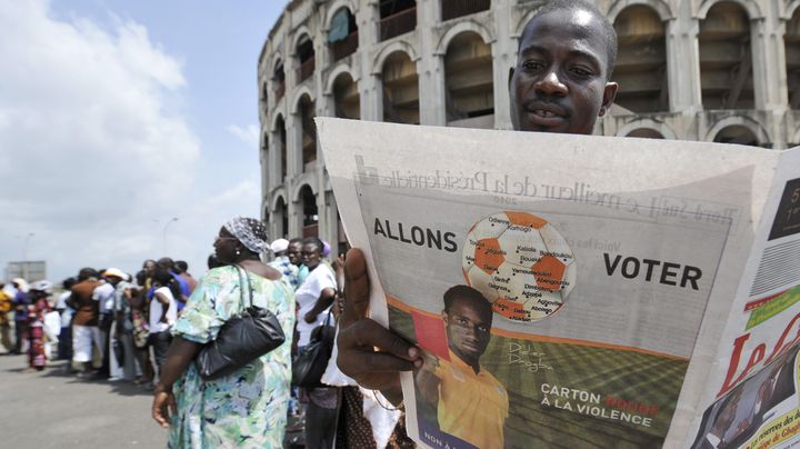 Un Ivoirien lit un journal avec en quatri&egrave;me de couverture une publicit&eacute; o&ugrave; le footballeur Didier Drogba incite les gens &agrave; aller voter, le 25 novembre 2010, &agrave; Abidjan (C&ocirc;te d'Ivoire). (SIA KAMBOU / AFP)