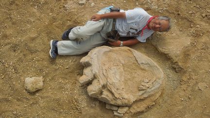 Shinobu Ishigaki, professeur à l'université d'Okayama, pose à côté de l'empreinte de dinosaure découverte dans le désert de Gobi (Mongolie), le 21 août 2016. (OKAYAMA UNIVERSITY OF SCIENCE AND MONGOLIAN ACADEMY OF SCIENCES JOINT EXPEDITION / AFP)