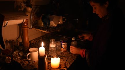 Une femme prépare du lait pour son enfant dans sa maison de Montevideo (Uruguay), lors d'une panne massive d'électricité, le 16 juin 2019.&nbsp; (MIGUEL ROJO / AFP)