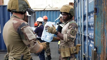 Des soldats déchargent des packs d'eau à destination des personnes les plus fragiles à Mayotte, le 20 septembre 2023. (CHAFION MADI / AFP)