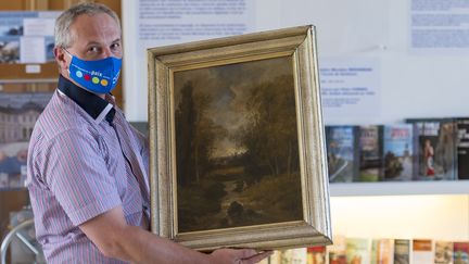 Philippe Hansch, directeur du&nbsp;Centre mondial de la paix à Verdun, présente un tableau du peintre français Nicolas Rousseau en août 2020.&nbsp; (JEAN-CHRISTOPHE VERHAEGEN / AFP)