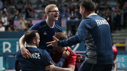 Au bout du suspense face à des pongistes particulièrement accrocheurs, Félix Lebrun vient d'offrir à ses coéquipiers la médaille de bronze par équipes. C'est la deuxième que remporte le prodige de 17 ans, dans ces JO, ici porté par son frère Alexis (en rouge) et Simon Gauzy (en bleu) et félicité par leur entraîneur, Nathaël Molin. (JUNG YEON-JE / AFP)