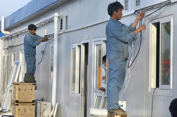 Des ouvriers réalisant des finitions sur le nouvel hôpital de Xiaotangshan, dans la banlieue de Pékin, construit pour soigner les malades atteints du Sras, le 29 avril 2003.&nbsp; (FREDERIC BROWN / AFP)