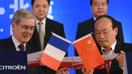 Philippe Varin, ancien patron de PSA Peugeot Citro&euml;n, signe un contrat avec Xu Ping, pr&eacute;sident de Dongfeng Motor&nbsp;Group, &agrave; P&eacute;kin (Chine), le 28 mars 2014. (GOH CHAI HIN / AFP)