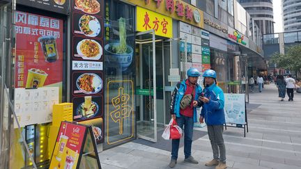 Deux passants devant un restaurant de nouilles de Lanzhou à Pékin, en octobre 2024. (SEBASTIEN BERRIOT / RADIOFRANCE)