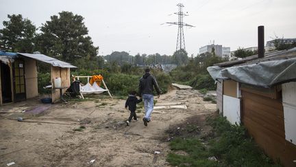 Un homme et un enfant traverse le camp de Roms de Grigny (Essonne), le 27 septembre 2013. (  MAXPPP)