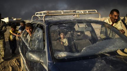 Des exilés irakiens poussent leur voiture jusqu'à un camp de réfugiés situé à Qayyarah, le 22 octobre 2016. La famille avait quitté Mossoul pour fuir les combats visant à reprendre la ville au groupe Etat islamique. (BULENT KILIC / AFP)