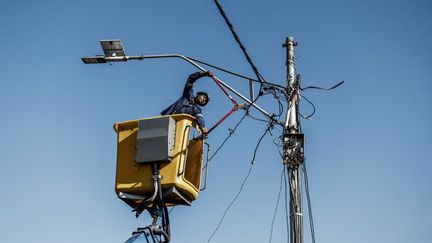 Un employé coupe un&nbsp;câble électrique&nbsp;branché illégalement par des hébitants dans la région de Brixton à Johannesburg,&nbsp; le 9 juin 2022.&nbsp; (MARCO LONGARI / AFP)