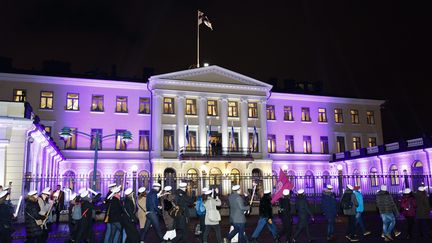 Le couple présidentiel salue des étudiants finlandais qui défilent devant le palais pour célébrrer les 100 ans de l'indépendance, à Helsinki (Finlande). (RONI REKOMAA / LEHTIKUVA)