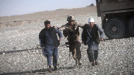  
	Un Marine américain aide des Afghans, blessés par des tirs d’insurgés, à rejoindre l’hélicoptère de l’unité médicale aérienne. (AFP PHOTO / BEHROUZ MEHRI)