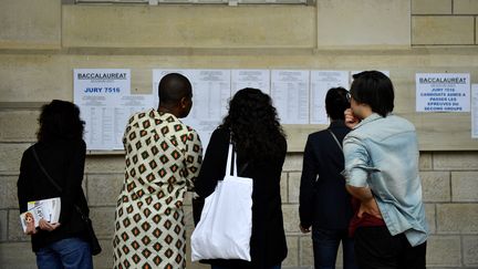 Des professeurs et des élèves regardent les résultats du baccalauréat au lycée Voltaire à Paris, le 4 juillet 2023. (JULIEN DE ROSA / AFP)