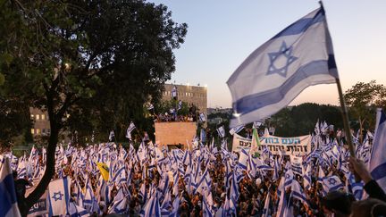 Des manifestants pro-gouvernementaux brandissent le drapeau israélien alors qu'ils se rassemblent près du parlement à Jérusalem, le 27 avril 2023. (AHMAD GHARABLI / AFP)