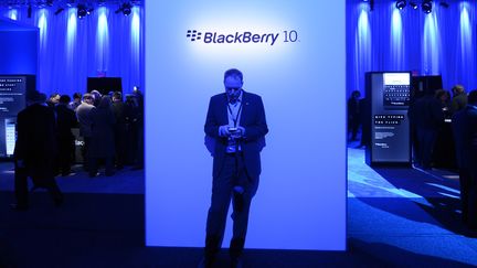 Un journaliste se tient devant un panneau du smartphone Blackberry 10, &agrave; l'occasion du lancement du t&eacute;l&eacute;phone, le 30 janvier 2013, &agrave; New York. (TIMOTHY A. CLARY / AFP)