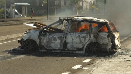 Une voiture en feu dans une rue de Fort-de-France, en Martinique, le 17 septembre 2024, après une nuit de violences urbaines. (THOMAS THURAR / AFP)