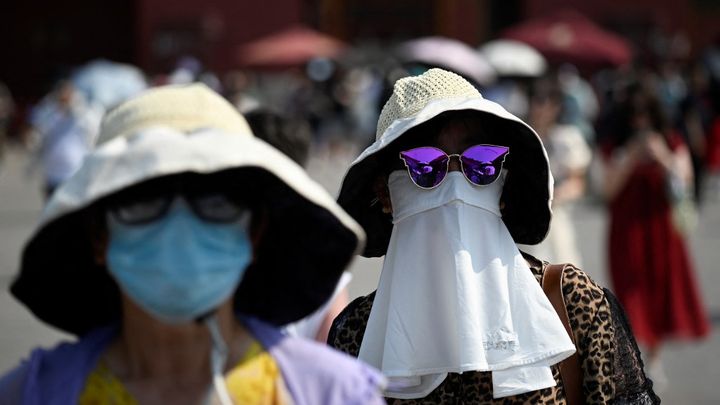 Une femme s'abrite sous un masque pour se protéger des fortes températures, à Pékin (Chine), le 16 juin 2023. (WANG ZHAO / AFP)