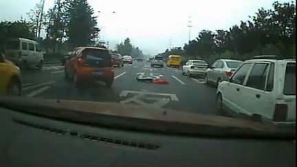 Capture d'&eacute;cran d'une vid&eacute;o mise en ligne sur le site Youku. On y voit une voiture contournant le corps d'une femme qui vient de se jeter d'un pont, pr&egrave;s de Chengdu (Chine), le 2 novembre 2011. (FTVi)