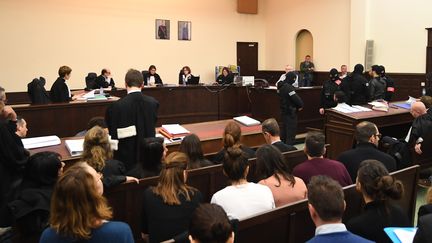 Salah Abdeslam, en veste blanche et de dos au premier rang, et son complice présume Sofiane Ayari, en gris et debout à sa droite, s'assoient dans la salle d'audience du palais de justice de Bruxelles au premier jour de leur procès, le 5 février 2018. (EMMANUEL DUNAND / AFP)