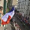 Une Parisienne agite un drapeau à sa fenêtre lors du passage de la course cycliste des Jeux olympiques, dans le quartier de Montmartre, le 4 août 2024. (JULIEN DE ROSA / AFP)