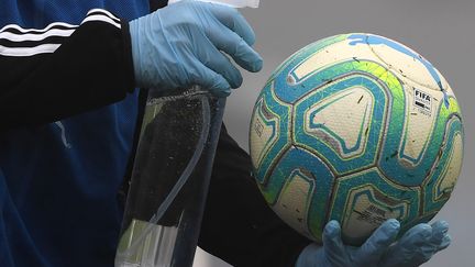 Un homme désinfecte un ballon de football avant un match, à Montevideo, en Uruguay, le 9 août 2020.&nbsp; (PABLO PORCIUNCULA / AFP)