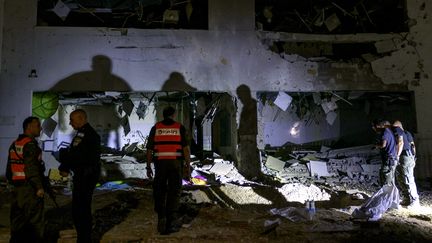 Des forces de l'ordre israéliennes devant une école endommagée par des frappes iraniennes, le 1er octobre 2024 à Guedera (Israël). (MENAHEM KAHANA / AFP)