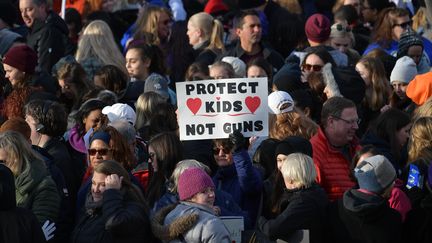 Une participante du défilé organisé samedi 24 mars 2018 à Washington pour réclamer plus de contrôle des armes à feu brandit une pancarte où il est inscrit "Protégez les enfants, pas les armes". (MANDEL NGAN / AFP)