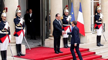 Emmanuel Macron est accueilli en haut des marches du perron présidentiel par une sobre poignée de main et un sourire aux lèvres par François Hollande.&nbsp; (GONZALO FUENTES / REUTERS)