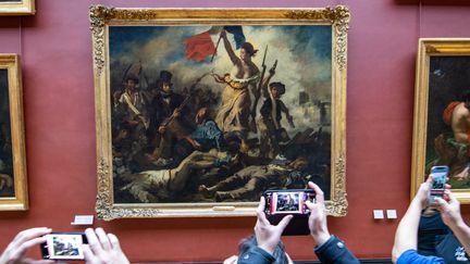 Le tableau "La liberté guidant le peuple" d'Eugène Delacroix (1798-1863), photographié par des visiteurs au musée du Louvre, le 26 décembre 2022 (PANAYOTIS PAVLEAS / HANS LUCAS)