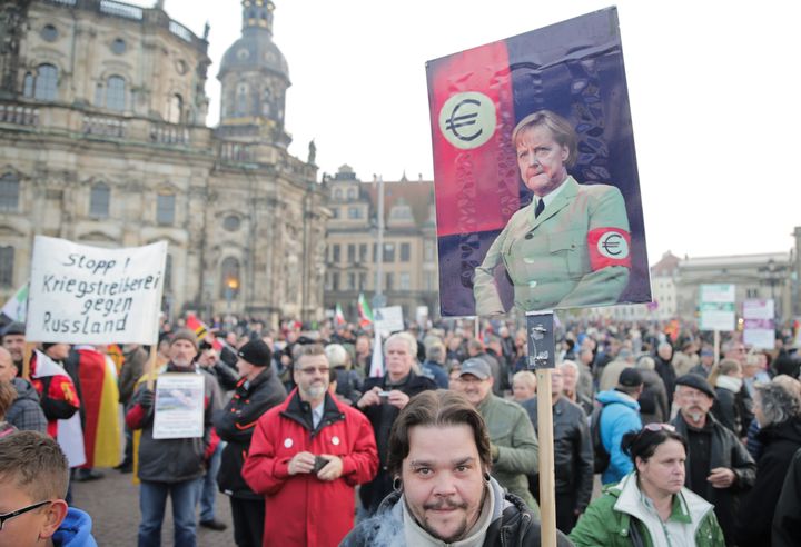 Un partisan de Pegida porte une pancarte montrant la chanceli&egrave;re allemande, Angela Merkel, v&ecirc;tue d'un uniforme nazi. (MAXPPP)