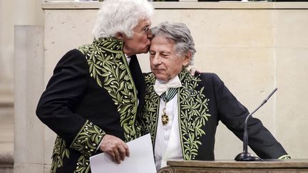 Le r&eacute;alisateur fran&ccedil;ais Jean-Jacques Annaud (G) embrasse Roman Polanski lors d'une session &agrave; l'Acad&eacute;mie des Beaux-Arts &agrave; Paris, le 28 mars 2012. (JEAN-PHILIPPE KSIAZEK / AFP)