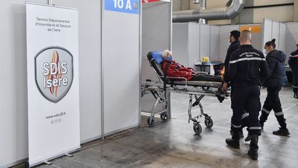 Des pompiers déplacent un homme âgé au&nbsp;vaccinodrome d'Alpexpo, à Grenoble (Isère), le 9 avril 2021. (PHILIPPE DESMAZES / AFP)