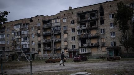 Une personne marche à côté d'un immeuble endommagé par l'invasion de la Russie à Kiev (Ukraine), le 7 octobre 2023. (OZGE ELIF KIZIL / ANADOLU AGENCY / AFP)