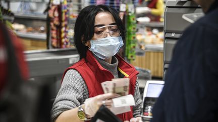 Une caissière porte un masque de protection et des gants, en pleine épidémie de coronavirus Covid-19, à Moscou, le 27 mars 2020. (ALEXANDER NEMENOV / AFP)