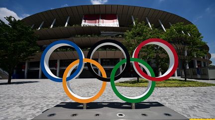 Les anneaux olympiques devant le stade olympique de Tokyo (Japon), le 19 juillet 2021, à quelques jours de l'ouverture des JO. (PHILIP FONG / AFP)