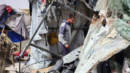 Un Palestinien sous une tente dévastée du camp de déplacés pris pour cible par l'armée israélienne à Rafah, dans la bande de Gaza, le 28 mai 2024. (HANI ALSHAER / ANADOLU / AFP)