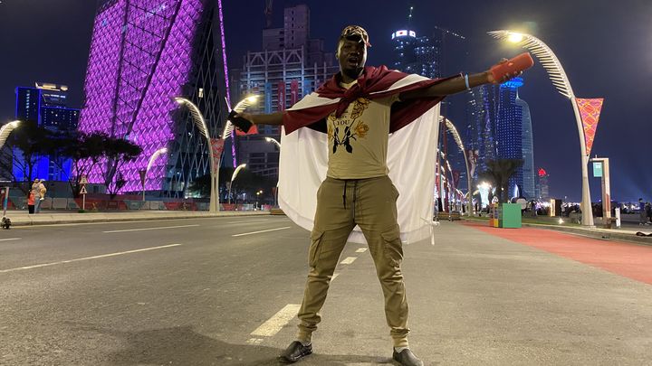 Edward, Ougandais, arbore le drapeau qatari dans les rues de Doha, le 19 novembre 2022. (RAPHAEL GODET / FRANCEINFO)