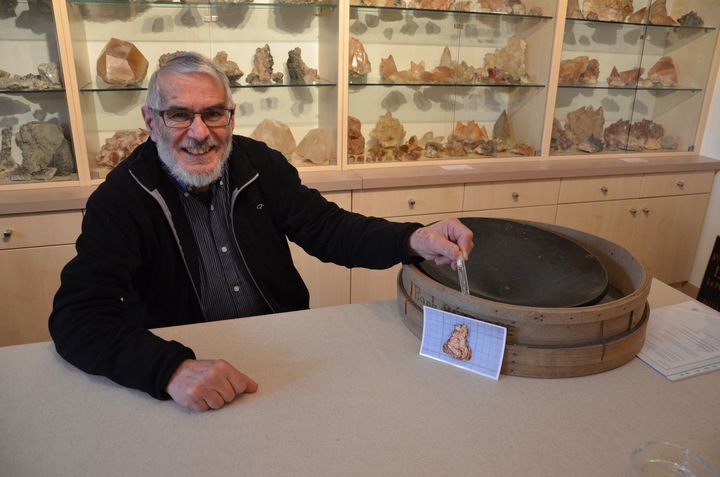 Rapha&euml;l Rethor&eacute; pose avec quelques paillettes d'or, son mat&eacute;riel d'orpaillage et la photo de la plus grosse p&eacute;pite (0,5 cm) jamais d&eacute;couverte &agrave; Saint-Pierre-Montlimart (Maine-et-Loire), le 15 avril 2015. (THOMAS BAIETTO / FRANCETV INFO)