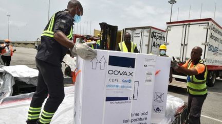 Des travailleurs déchargent une cargaison de vaccin AstraZeneca contre le Covid-19 à l'aéroport d'Abidjan, en Côte d'Ivoire, le 26 février 2021. (SIA KAMBOU / AFP)