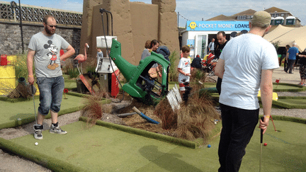 "Un mini-golf fou aux airs de califat du p&eacute;trole", promet Dismaland. A l'arri&egrave;re-plan, un office propose des pr&ecirc;ts usuriers aux enfants, qui souhaitent obtenir de l'argent de poche. (STEVE BEALING / LANDM / NEWSCOM / SIPA)