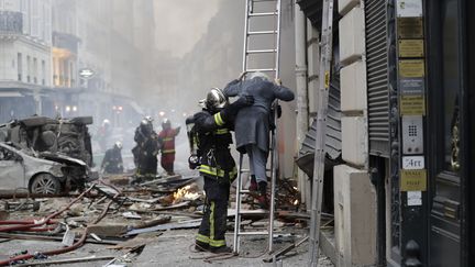 Un pompier aidant une sinistrée de la rue de Trévise, à Paris, le 12 janvier 2019. (THOMAS SAMSON / AFP)