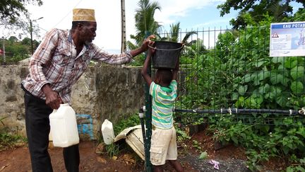 Des habitants remplissent des bidons à un point d'eau potable à Tsararano (Mayotte), le 27 décembre 2017. (ORNELLA LAMBERTI / AFP)