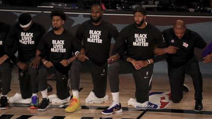 Les basketteurs des Los Angeles Lakers, dont LeBron James (au centre), s'agenouillent pendant l'hymne américain pour protester contre les discriminations raciales, le 31 juillet 2020 à Lake Buena Vista (Etats-Unis). (MIKE EHRMANN/AP/SIPA / SIPA)