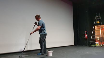 Emmanuel Bizot, fils de Léonie et gérant du cinéma, en train de repeindre la scène. (Boris Loumagne / Radio France)