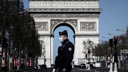 Un policier portant un masque, lors d'une opération de contrôle sur les Champs-Elysées, à Paris, le 23 mars 2020. Photo d'illustration. (PHILIPPE LOPEZ / AFP)