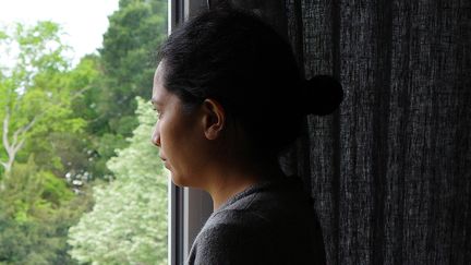 Une femme seule regarde par la fenêtre de son appartement lors du premier confinement. Illustration sur le thème de l'isolement, de la dépression et covid longs.&nbsp; (MATHIEU THOMASSET / HANS LUCAS via AFP)