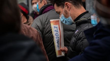 Un employé tient dans sa main un exemplaire du journal l'Equipe pendant une manifestation de la rédaction devant le siège social du groupe.  (MARTIN BUREAU / AFP)