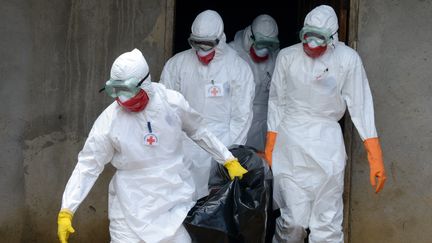 Des employ&eacute;s de la Croix-Rouge lib&eacute;rienne &eacute;vacuent le corps d'un malade du virus Ebola, le 4 septembre 2014 &agrave; Monrovia (Liberia). (DOMINIQUE FAGET / AFP)